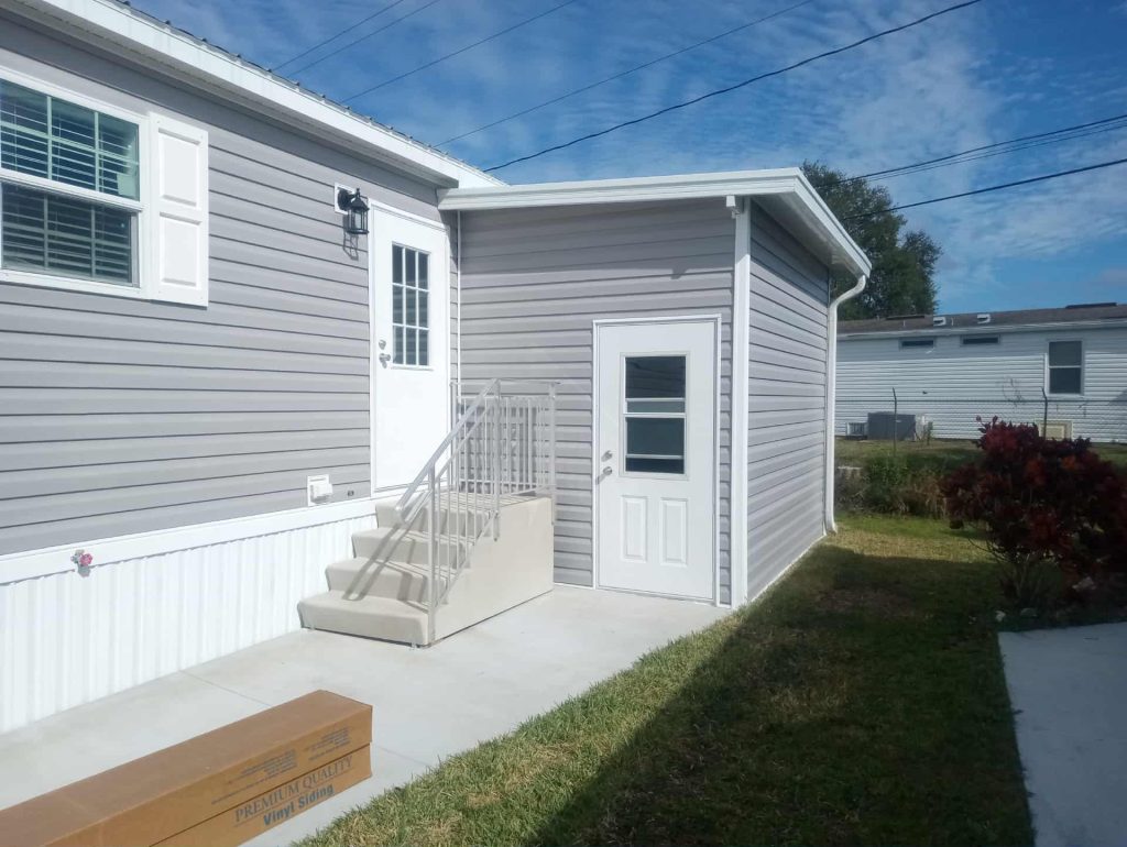 Completed wood frame shed with pan roof next to modular home in Cocoa