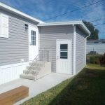 Completed wood frame shed with pan roof next to modular home in Cocoa