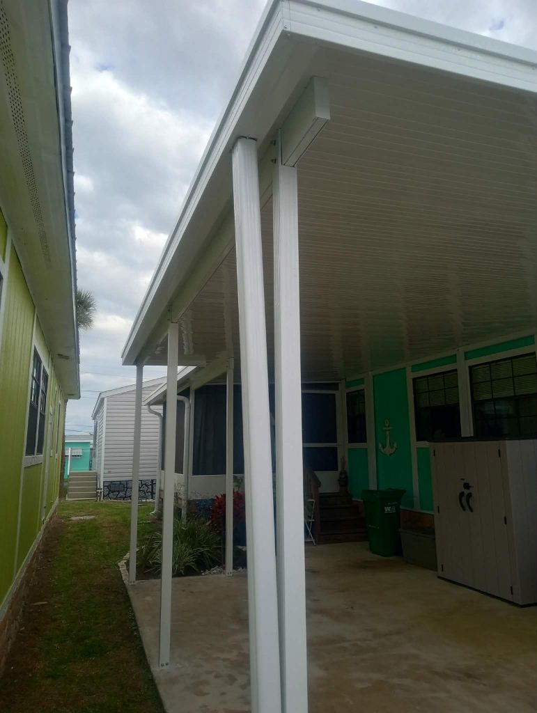 Side angle view of aluminum pan roof carport with white posts on Merritt Island modular home