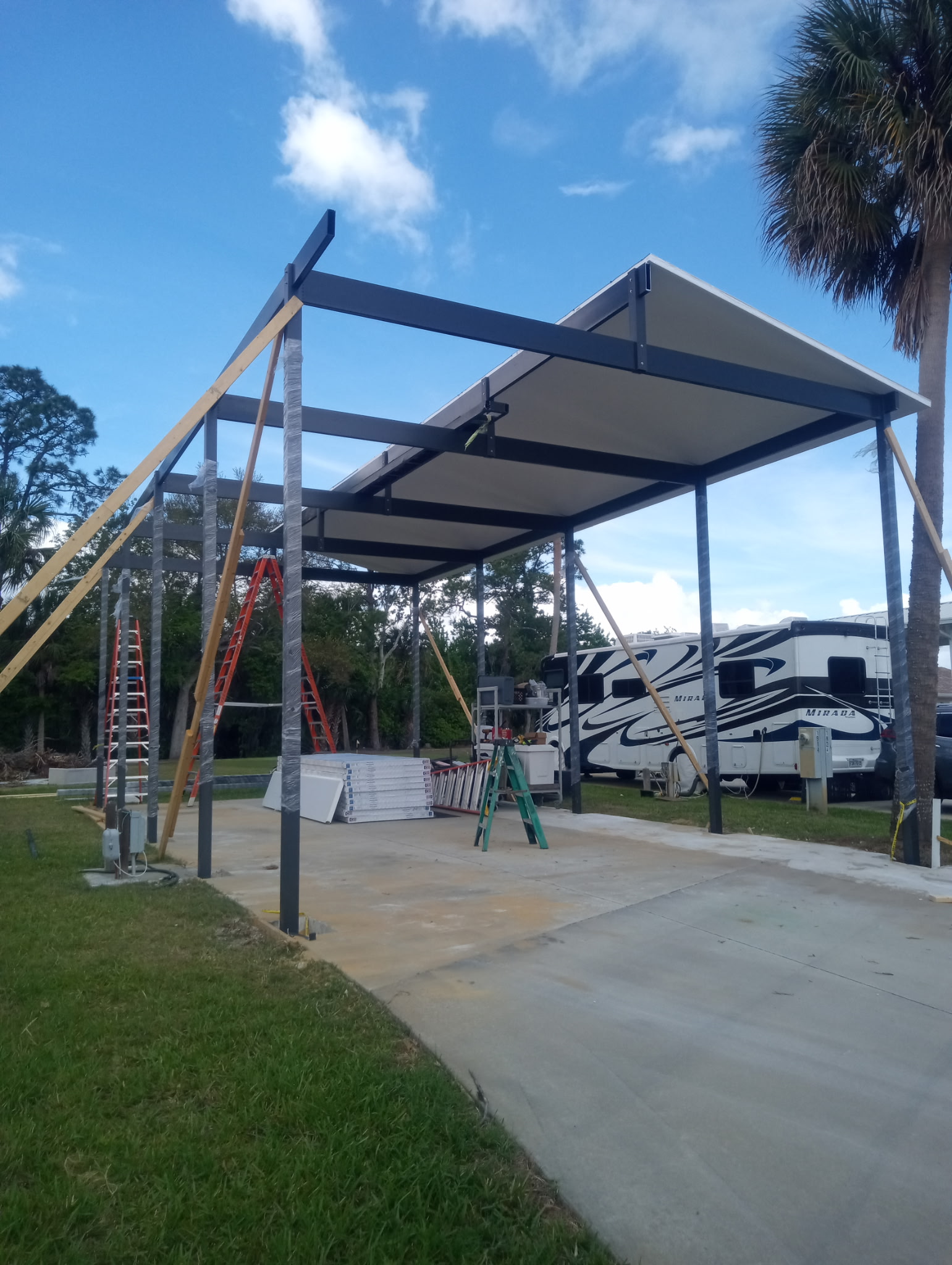 Mid-construction view of freestanding motorhome carport showing 2x10 cross beams in Titusville Florida