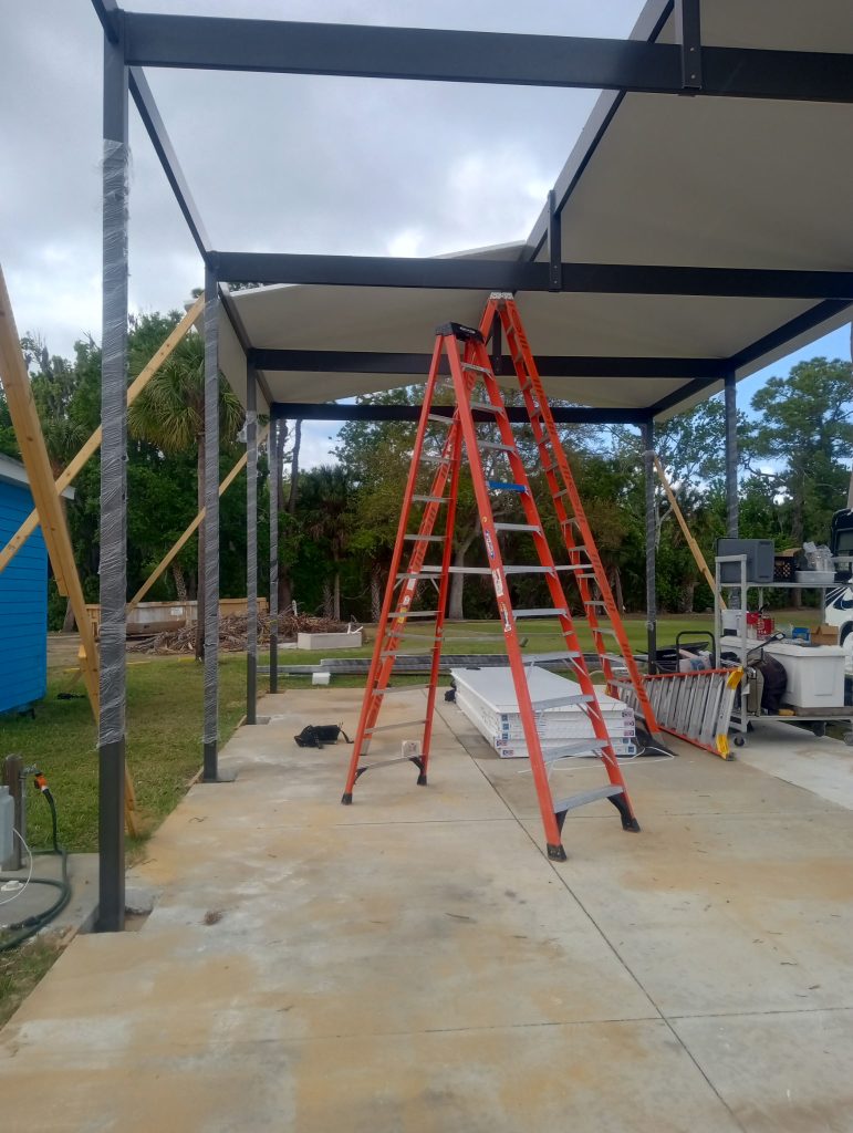 Wide angle view of large aluminum motorhome carport under construction with insulated roof panels Titusville