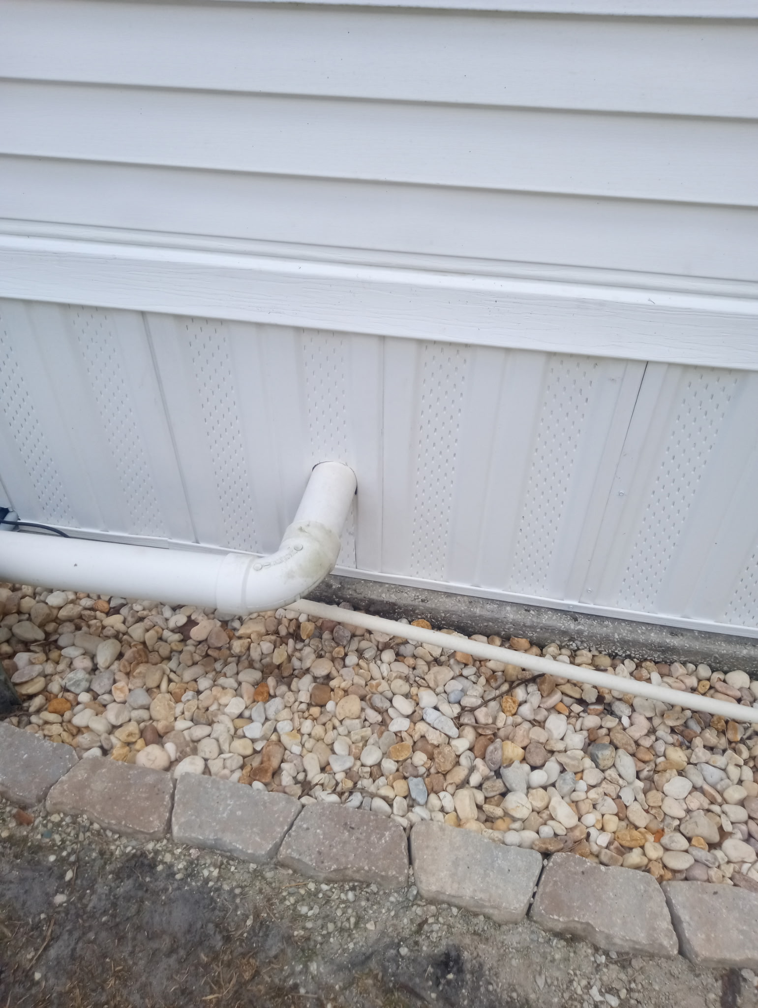 Vented vinyl skirting cut around PVC drainage pipe at mobile home in Titusville Florida
