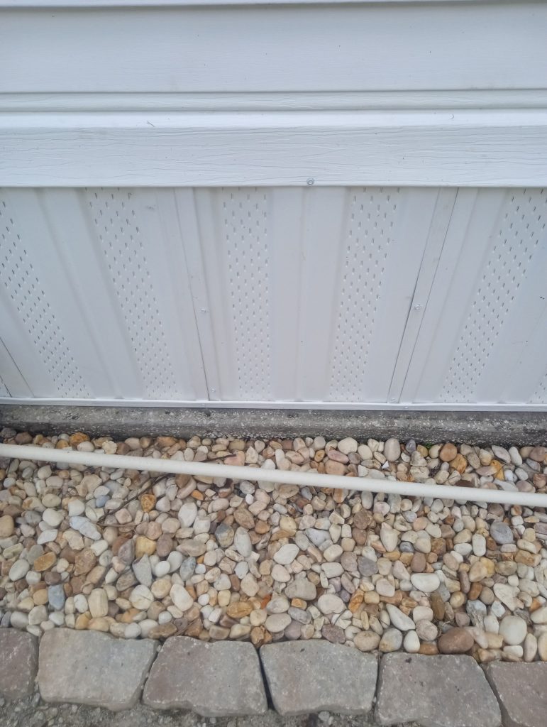 Vinyl skirting custom fit around electrical disconnect and PVC drain plumbing on Titusville mobile home